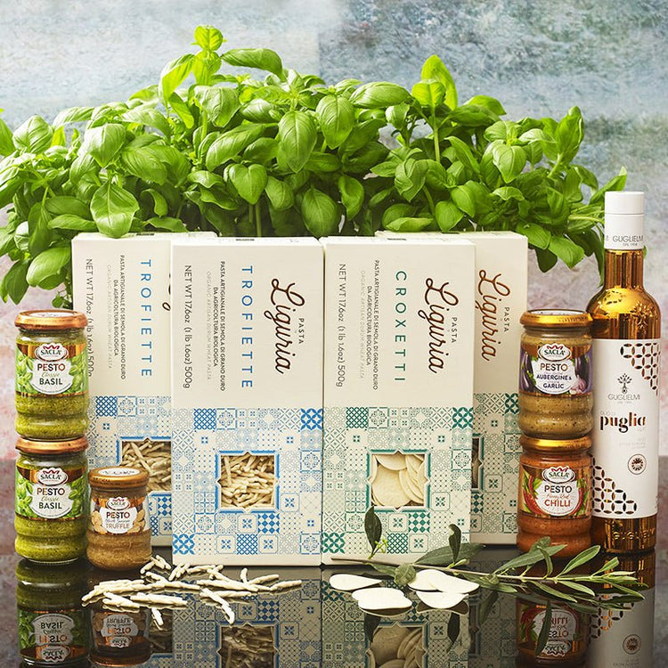 Liguria Trofiette and Liguria Croxetti Italian Pasta in contempory style boxed packaging.. Sacla Pesto range and Puglia Olive Oil in stunning Copper glass bottle. With Basil plant and Olive leaves.